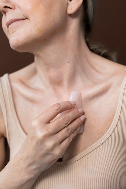 High angle old woman using gua sha