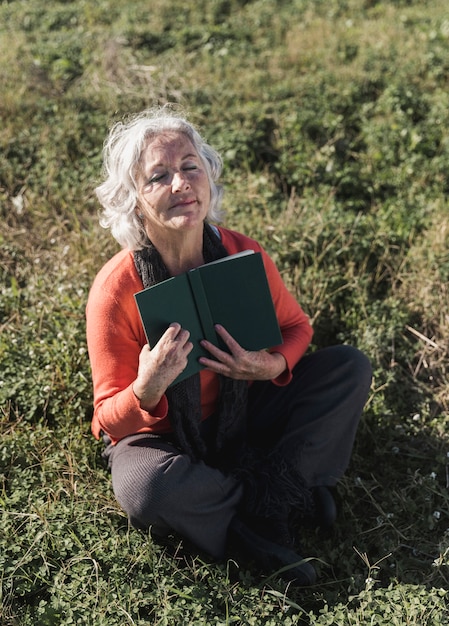 High angle old woman with book outdoors