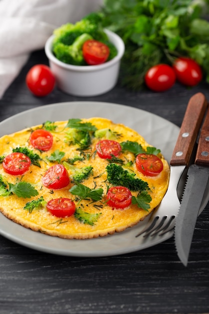 High angle of omelette for breakfast with tomatoes and cutlery