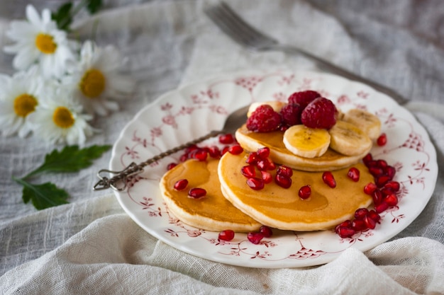 Free photo high angle pancakes with pomegranate seeds bananas and raspberries