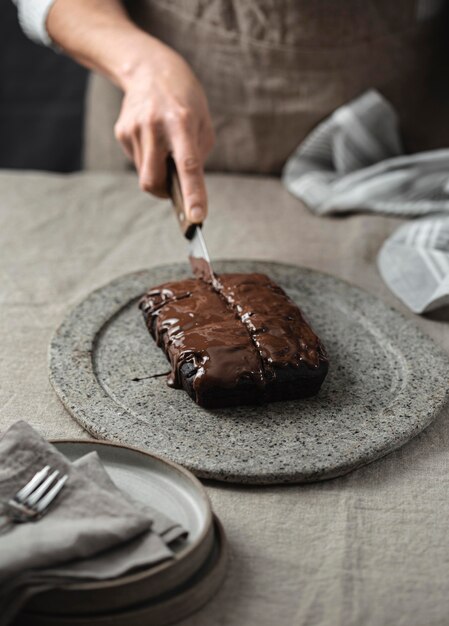 High angle of pastry chef cutting into chocolate cake