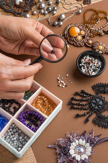 Free photo high angle of person doing bead work with magnifying glass