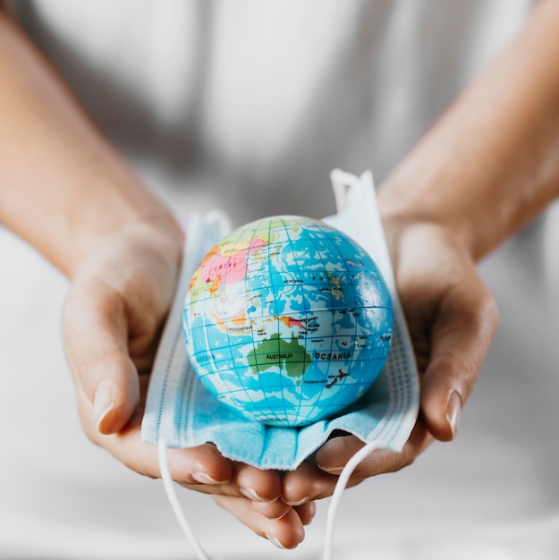 Free photo high angle of person holding medical mask with earth globe