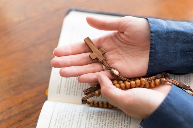 Free Photo high angle of person holding rosary with holy book open