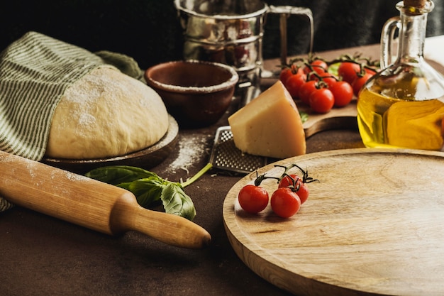 Free photo high angle of pizza dough with wooden board and parmesan cheese