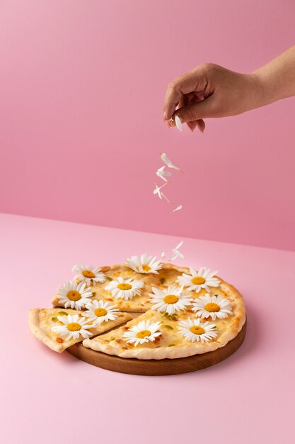 High angle pizza with flowers on pink background