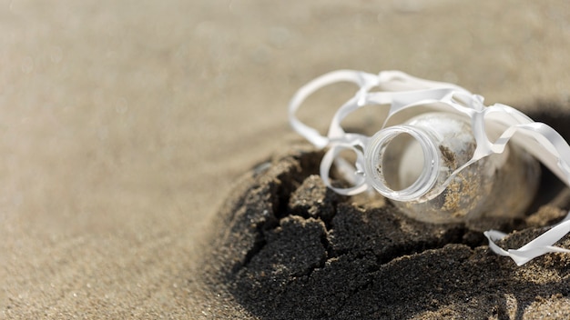 Free photo high angle plastic bottle in sand