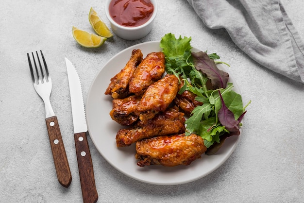 High angle of plate with fried chicken and salad with sauce and cutlery