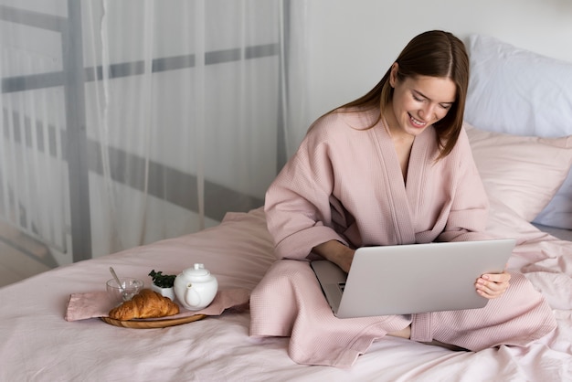 High angle pretty woman in robe checking her laptop