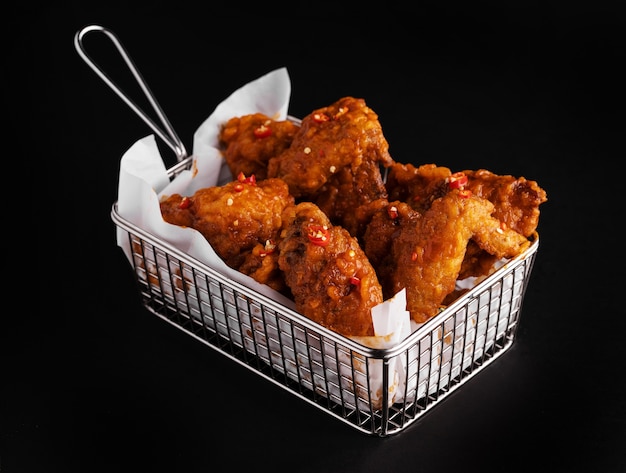 High angle shot of a basket of delicious fried chicken on a black surface