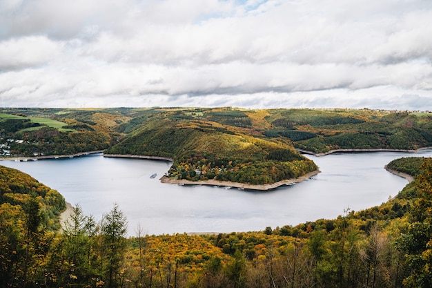 Free photo high angle shot of a beautiful lake surrounded by hills in autumn under the cloudy sky