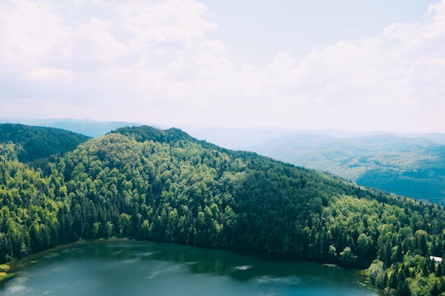 High angle shot of a beautiful lake surrounded by tree covered mountains under the cloudy sky