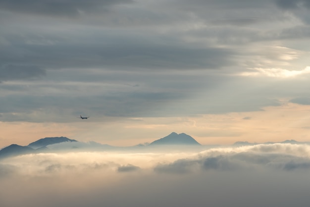 High angle shot of the beautiful mountain tops visible through the clouds and fog