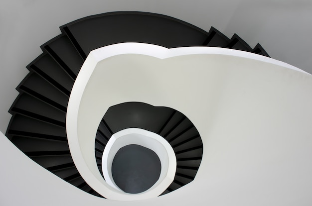 High angle shot of a black stairway going down surrounded by white walls