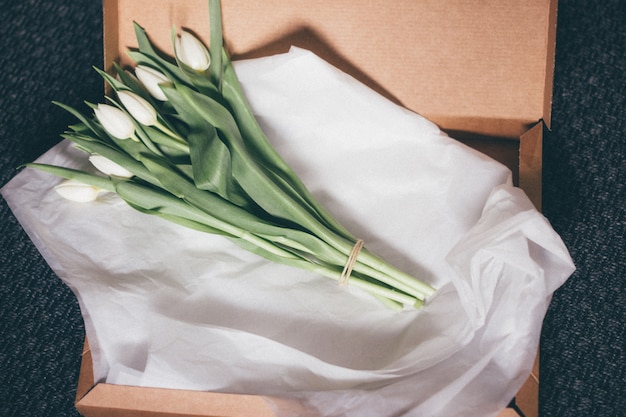 Free photo high angle shot of a bouquet of beautiful white tulips on a white paper