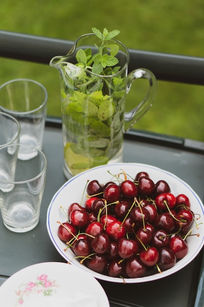 Free Photo high angle shot of cherries plate near mint lemonade on a black table