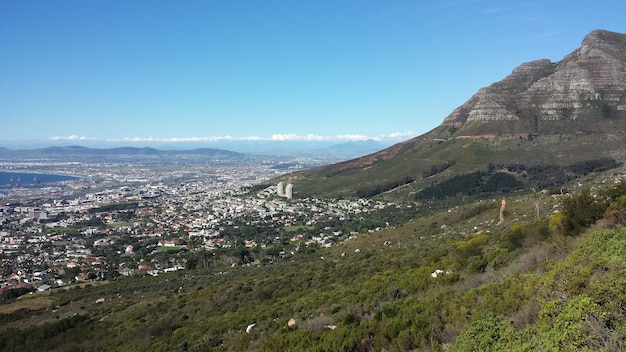 High angle shot of a city at the foot of a beautiful mountain under a clear blue sky