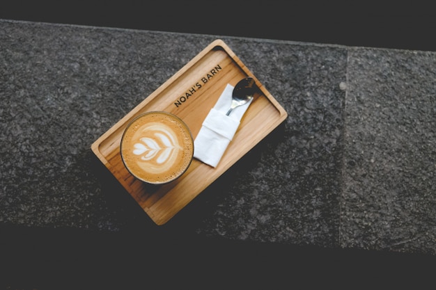 High angle shot of a cup of Latte art on a wooden tray