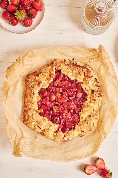 Free photo high angle shot of delicious rhubarb strawberries gallate cake with ingredients on a white table