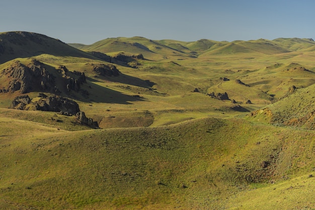 Free Photo high angle shot of empty grassy hills with a blue sky in the background at daytime