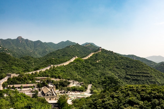 Free photo high angle shot of the famous great wall of china surrounded by green trees in summer