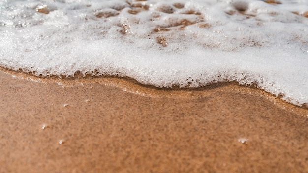 Free photo high angle shot of the foamy waves coming towards the sandy beach