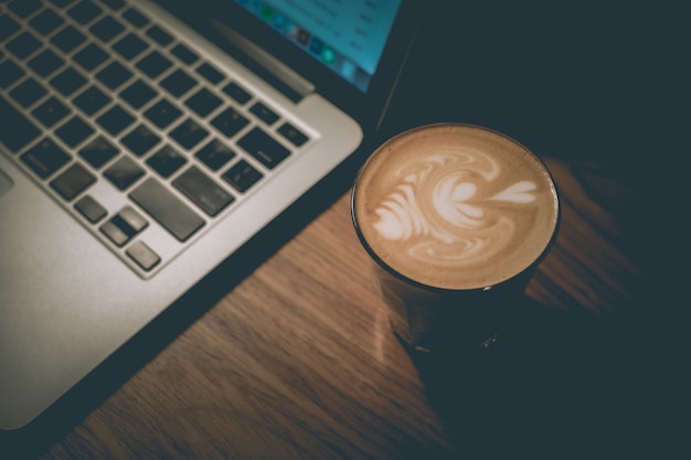 Free photo high angle shot of a glass of coffee next to a laptop