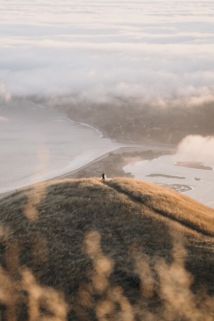 High angle shot of hills of different sizes surrounding the calm ocean