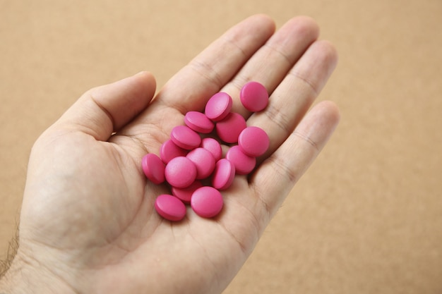 High angle shot of a human's hand with a handful of pink pills