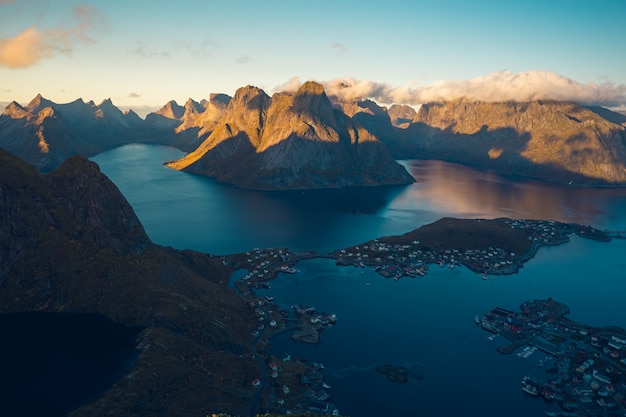 High angle shot of a lake on a summit surrounded by rocky mountains covered with white clouds