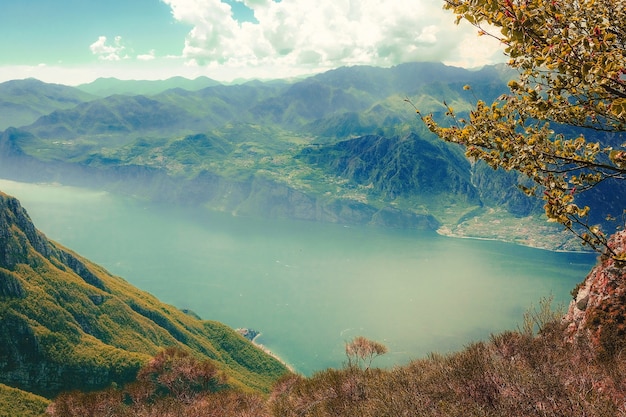 Free photo high angle shot of a lake surrounded by green mountains covered in fog under the cloudy sky