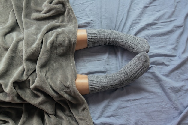 Free Photo high angle shot of the legs of a female in grey knitted socks under the blanket