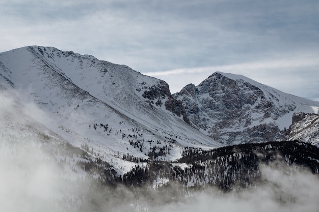 Free photo high angle shot of the mountains covered with snow under the cloudy sky