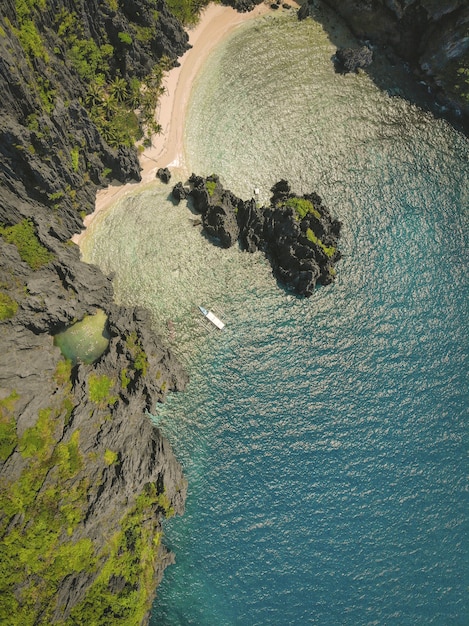 High angle shot of the ocean and the beach surrounded by moss covered cliffs