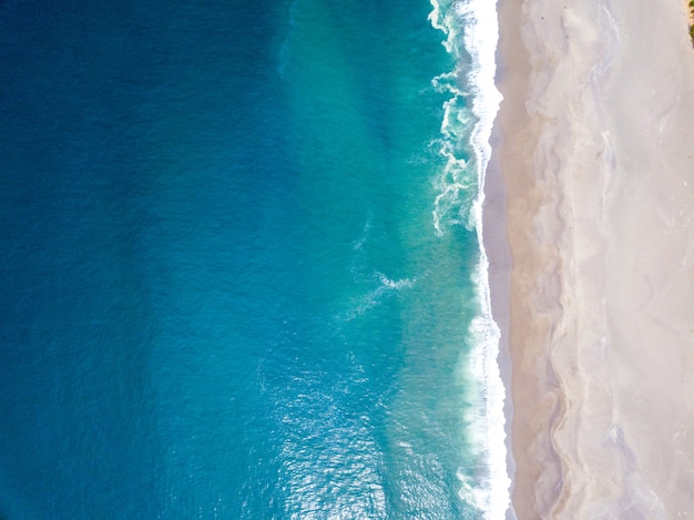 High angle shot of the ocean waves meeting the shore