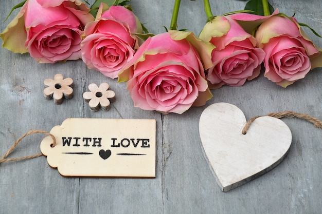 Free photo high angle shot of pink roses with other decorations on a wooden surface