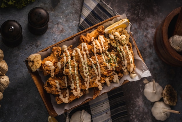 High angle shot of a plate of delicious fried chicken and some garlic on a table