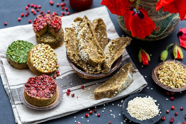 High angle shot of Raw vegan bread with red pepper, buckwheat, poppies on a dark tabletop