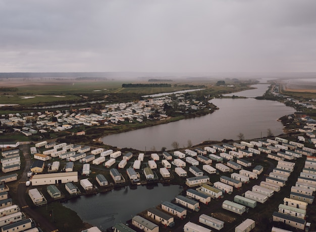 Free photo high angle shot of the rectangle houses on the fields by a beautiful foggy pond