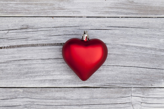 High angle shot of a red heart-shaped Christmas ornament on a wooden surface