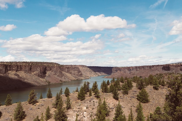 Free photo high angle shot of a river surrounded by hills in a deserted area under the bright cloudy sky