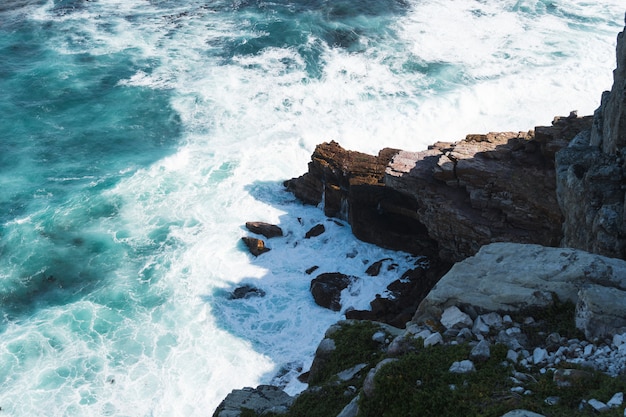 High angle shot of a rock formation near the body of turquoise water