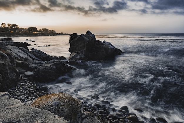 Free Photo high angle shot of small rocks on the shore of the sea under the cloudy evening sky