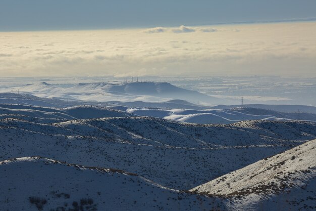 High angle shot of snowy mountains with a blue cloudy sky  at daytime