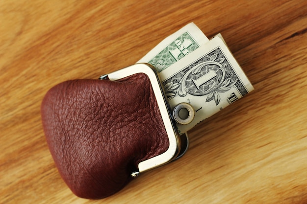 High angle shot of some cash in a leather change purse on a wooden surface