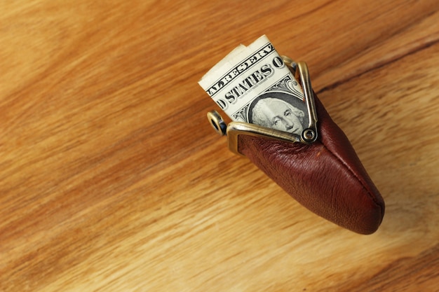 High angle shot of some cash in a leather change purse on a wooden surface