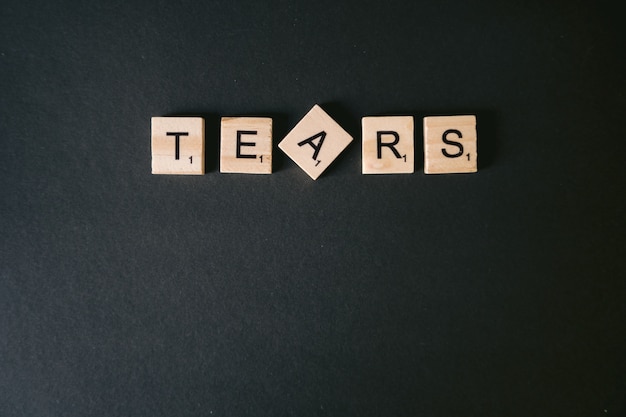 Free photo high angle shot of tears message on a black wall