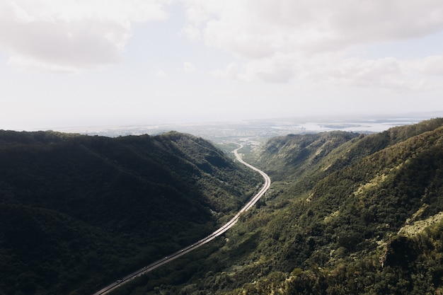 High angle shot of a valley road with a cloudy blue sky