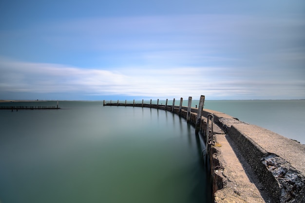 High angle shot of a wooden deck leading to the sea under a blue clear sky