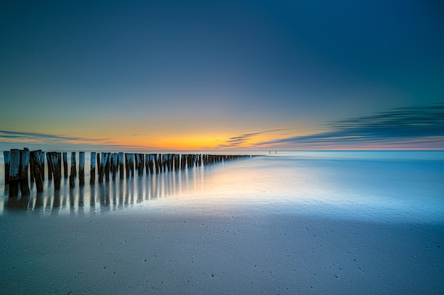 Free Photo high angle shot of a wooden deck on the seashore leading to the sea at sunset